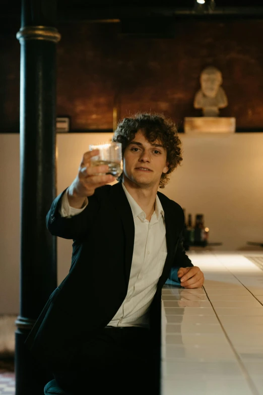 a man sitting at a bar with a glass in his hand, an album cover, by Jacob Toorenvliet, pexels contest winner, renaissance, joe keery, magnus carlsen, movie still frame, young spanish man