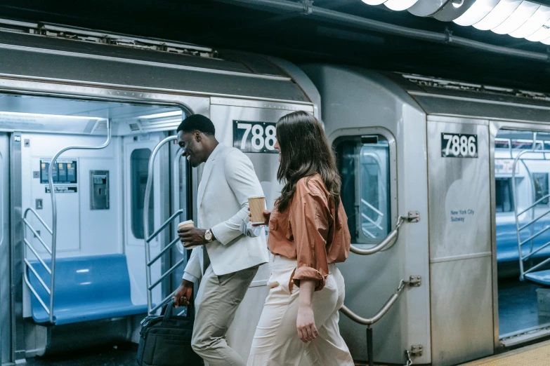 a couple of people that are standing in front of a train, by Carey Morris, pexels contest winner, nyc, carrying a tray, underground, wearing white clothes