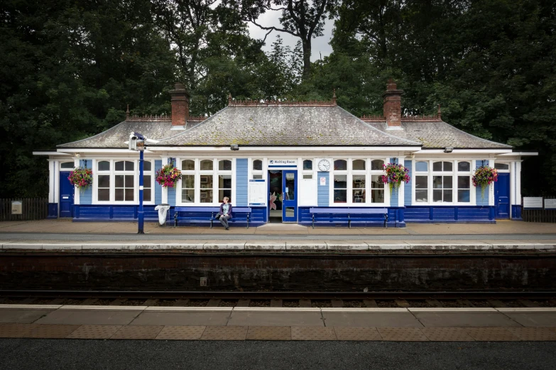a train station with a blue and white building, by Rachel Reckitt, unsplash, woodland grove, square, no reins, maryport