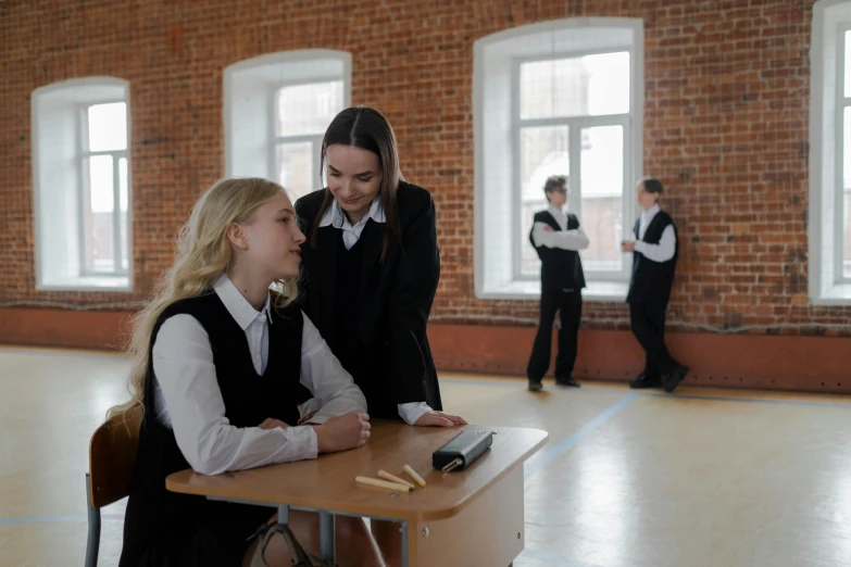 a couple of girls sitting at a desk in a room, trending on pexels, danube school, school girl in gothic dress, russian academic, as a strict school teacher ), in the high school gym