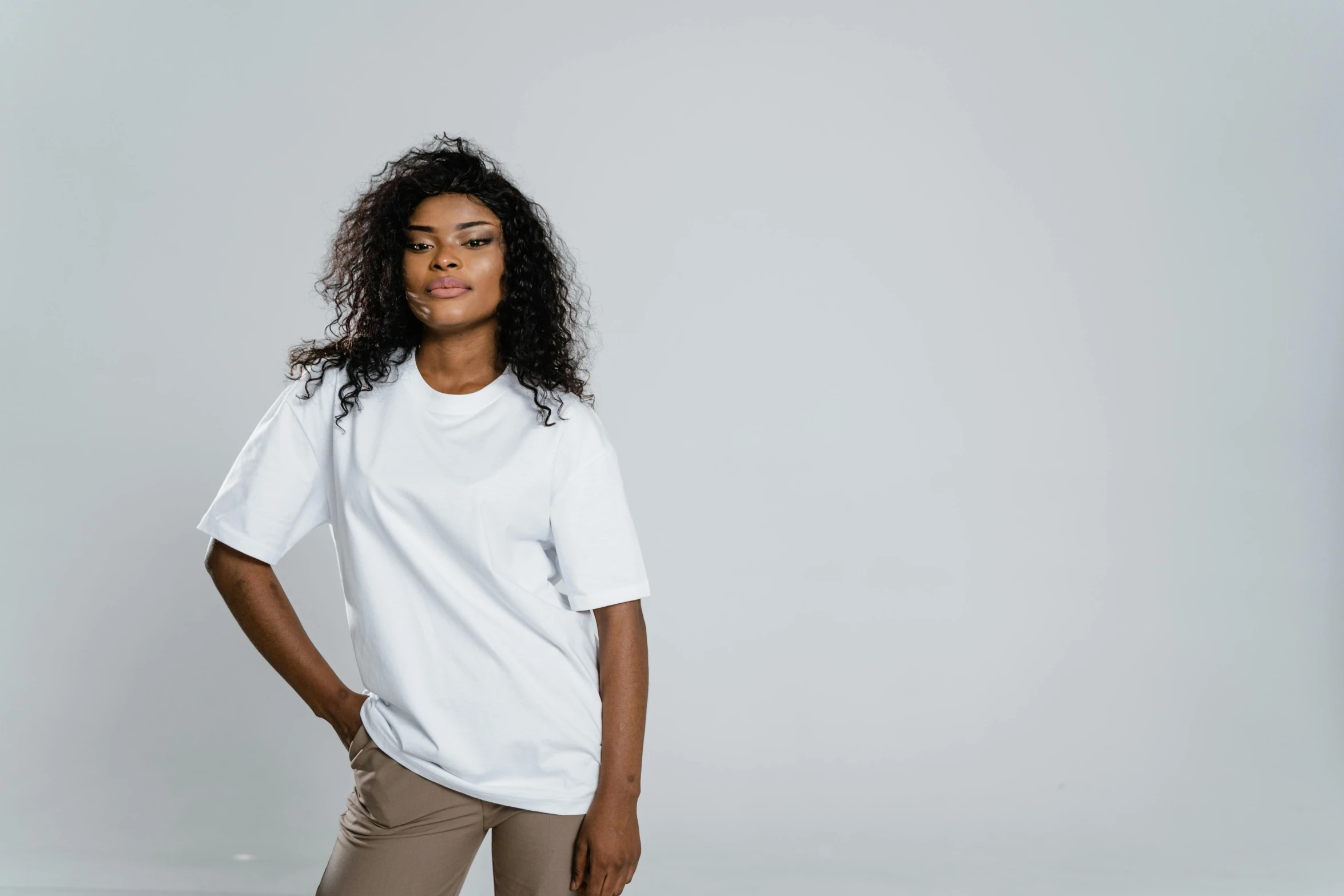 a woman in a white t - shirt standing with her hands on her hips, a character portrait, pexels contest winner, white ambient background, trending on r/streetwear, african american, profile shot