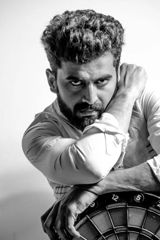 a black and white photo of a man leaning on a dart, by Max Dauthendey, a portrait of rahul kohli, angry look, square, herry cavill