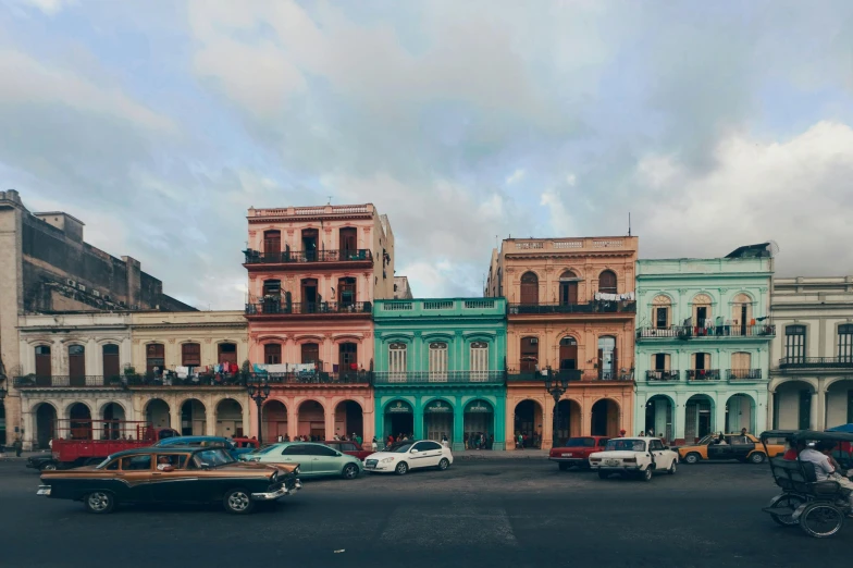 a group of cars driving down a street next to tall buildings, a colorized photo, pexels contest winner, hyperrealism, cuban setting, ornate palace made of green, a colorful, hd wallpaper