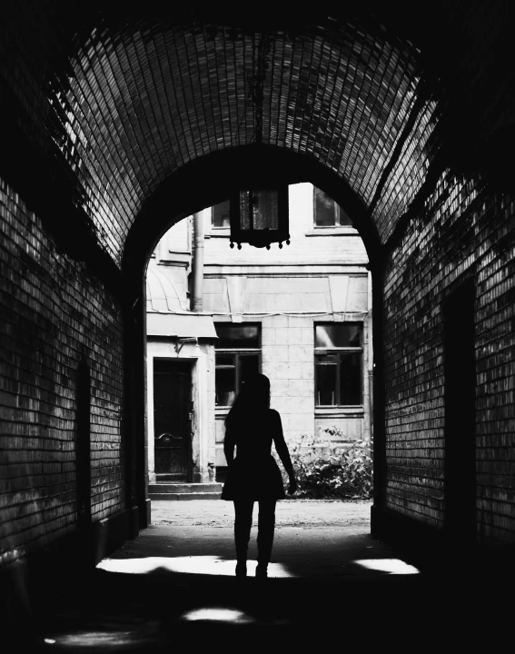 a black and white photo of a person walking through a tunnel, by Lucia Peka, post - soviet courtyard, silhouette!!!, brick, instagram picture