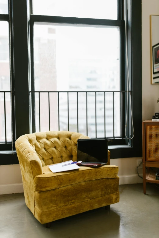 a yellow chair sitting in a living room next to a window, by Justin Sweet, unsplash, of mad men on madison avenue, city rooftop, home office interior, velvet couch