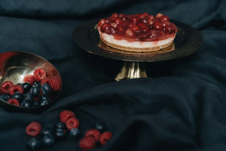 a dessert topped with raspberries and blueberries, a still life, by Emma Andijewska, pexels contest winner, background image, red theme, on a pedestal, silver platter