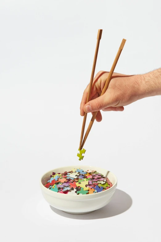 a person holding chopsticks over a bowl of cereal, a jigsaw puzzle, made of multicolored crystals, set against a white background, stick and poke, medium detail