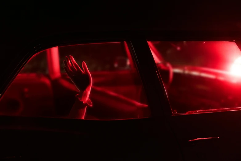 a person waving from their car window, as a red light shines