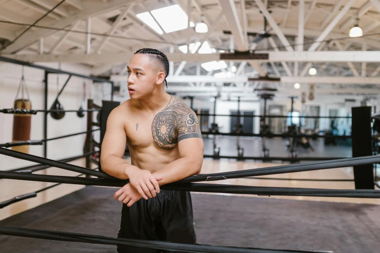 a shirtless man is leaning against the rail in a gym