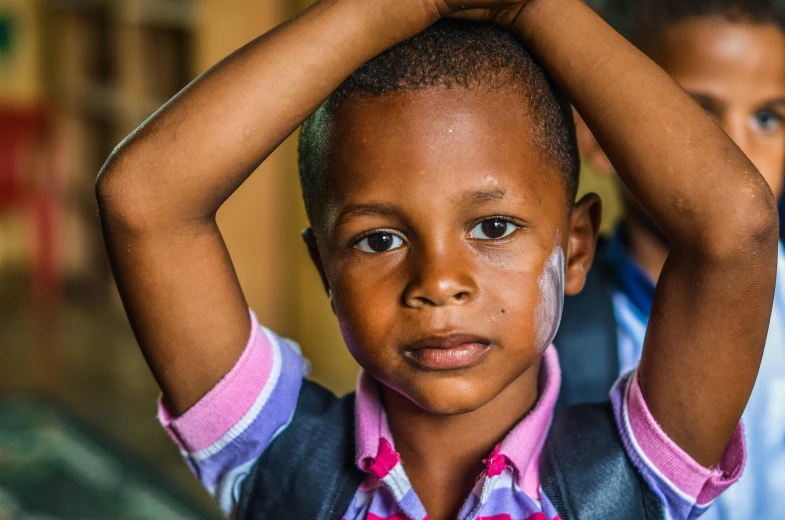 a young boy with his hands on his head, by Daniel Lieske, pexels contest winner, light skinned african young girl, schools, thumbnail, full frame image