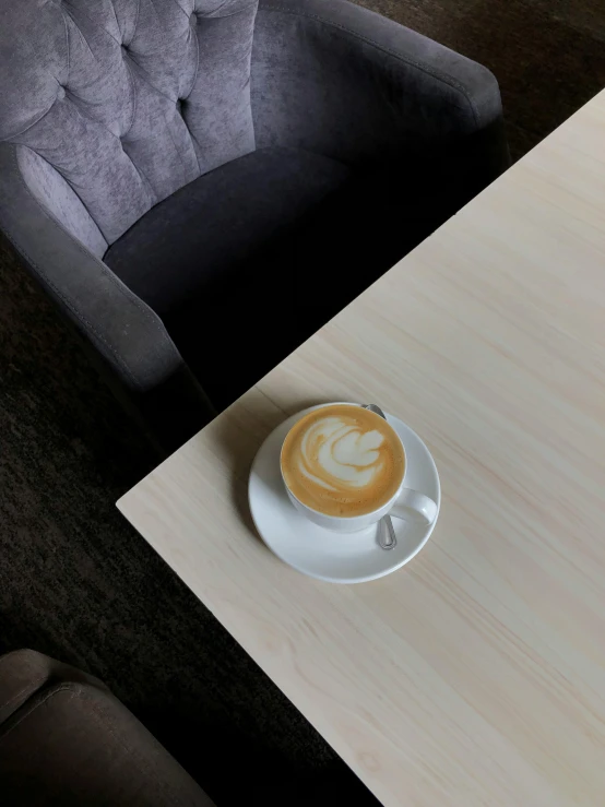 a cup of coffee sitting on top of a wooden table, by Robbie Trevino, velvet couch, thumbnail, cafe tables, simetrical medium shot