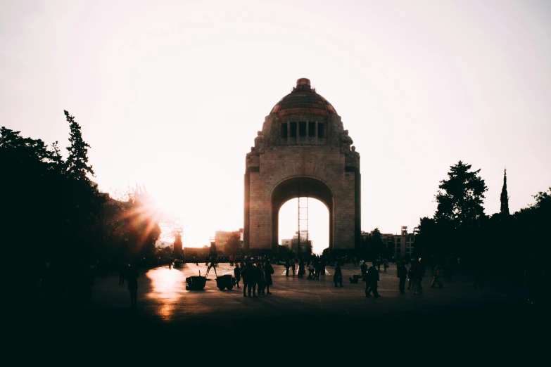 a group of people walking in front of a monument, by Matteo Pérez, pexels contest winner, sun flairs, mexican, arch, sunfaded