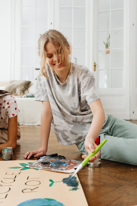 a couple of people that are sitting on the floor, an airbrush painting, inspired by Maler Müller, pexels contest winner, children playing with pogs, colouring - in sheet, teenage girl, at home