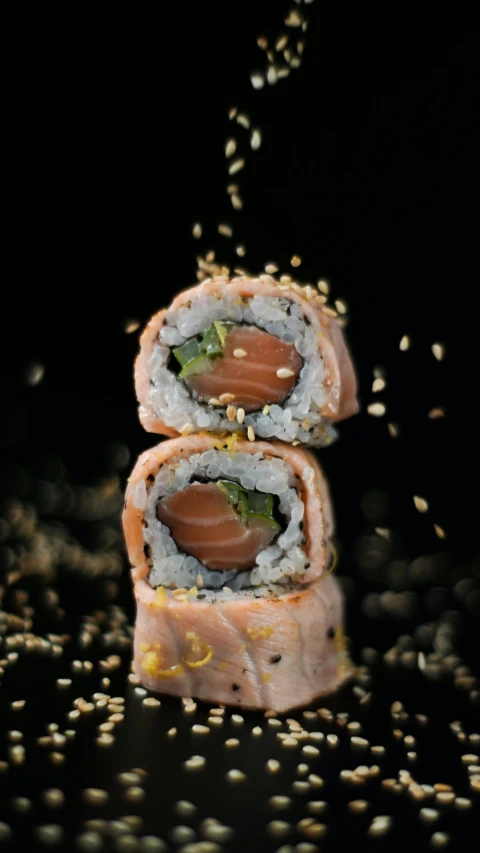 a meal of rice and sushi rolls is laying on a black surface