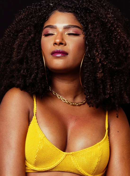 a woman in a yellow bra top posing for a picture, an album cover, by Lily Delissa Joseph, trending on pexels, happening, curls, profile image, curvaceous. detailed expression, soft portrait shot 8 k