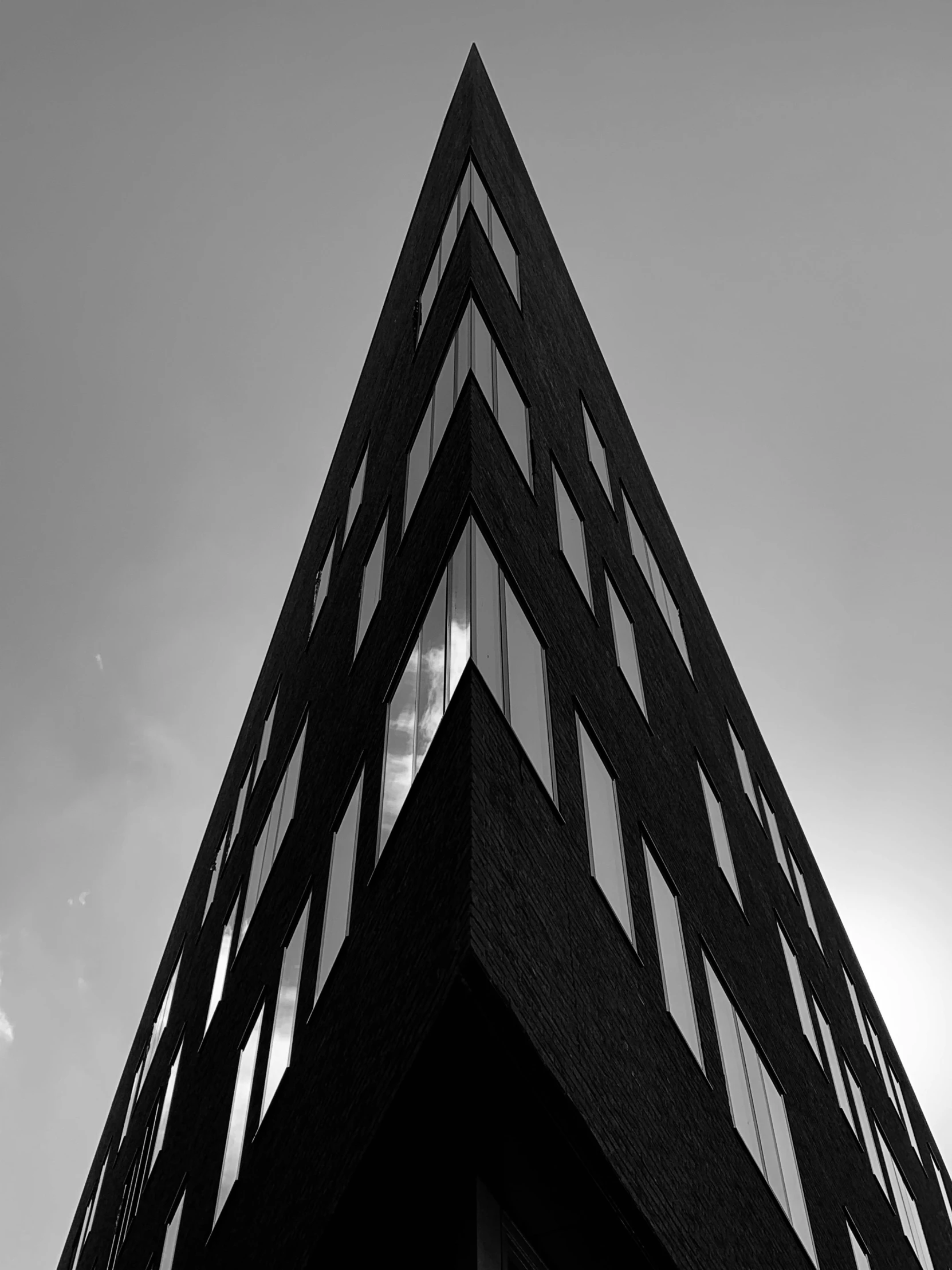 a black and white photo of a tall building, by Adam Rex, triangular face, low angle!!!!, dutch angle digital art, dramatic lighting - n 9