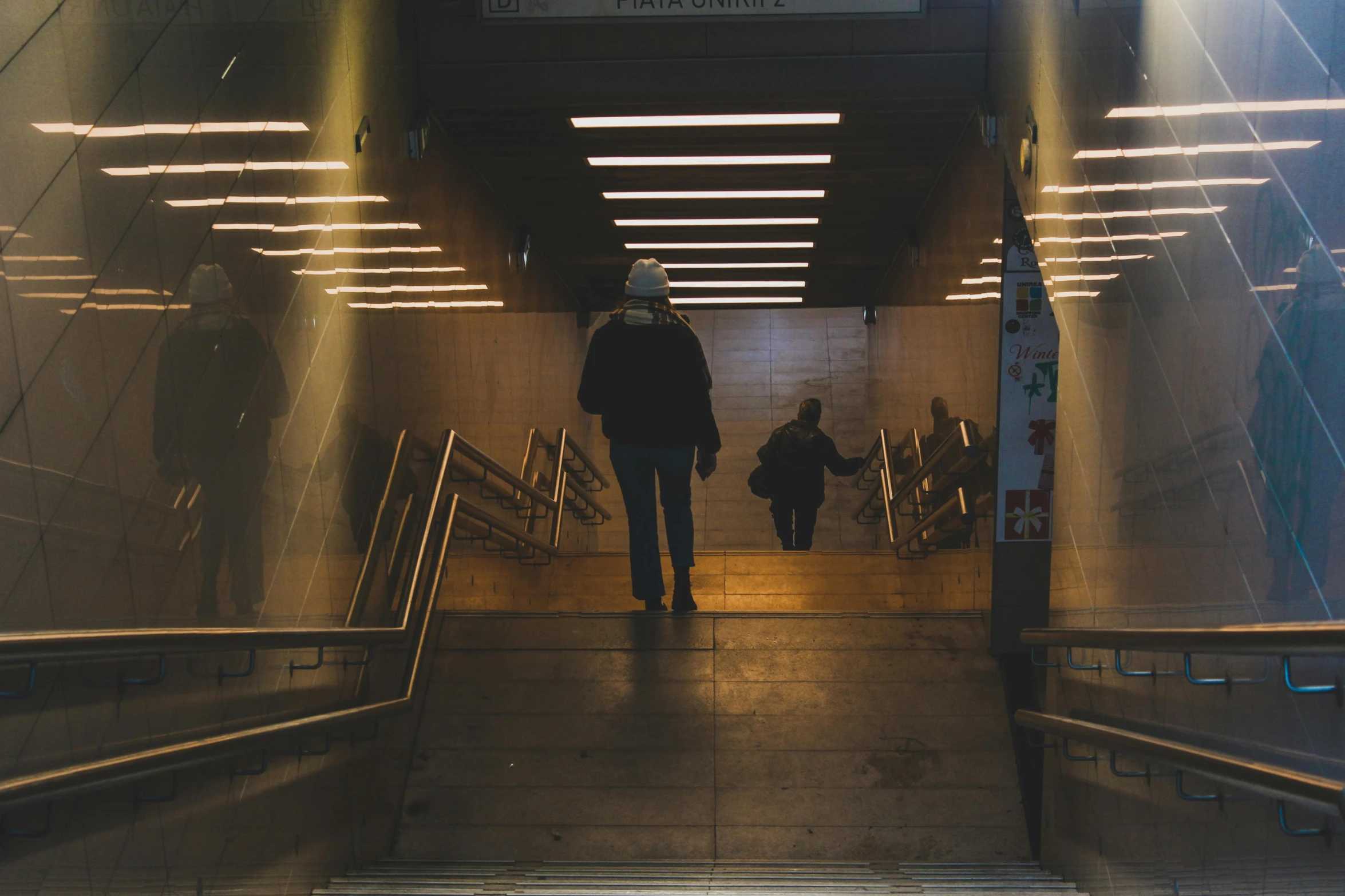 a couple of people that are walking down some stairs, by Elsa Bleda, pexels contest winner, happening, mta subway entrance, man standing, lights inside, the tunnel into winter