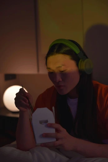 a woman sitting in bed reading a book, an album cover, inspired by Zhu Da, wearing a gaming headset, studio ambient lighting, working in her science lab, eating