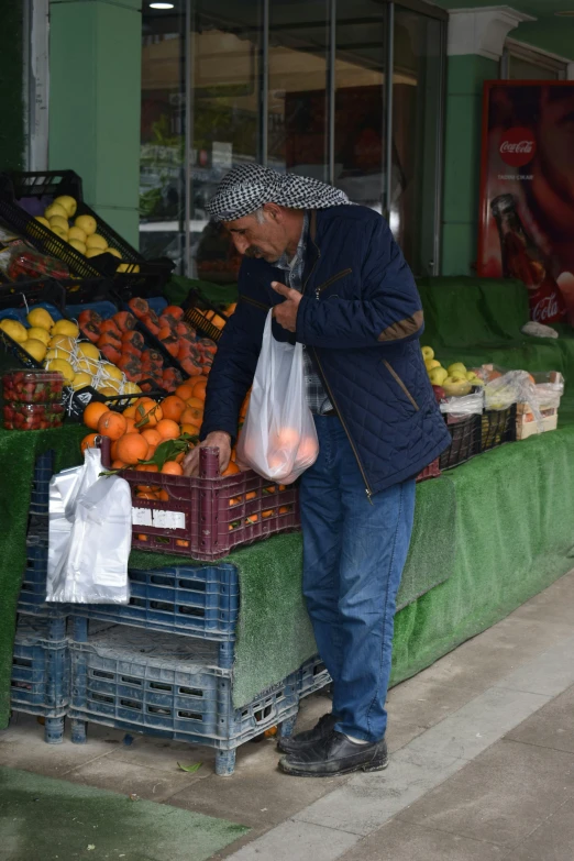 a man standing in front of a fruit stand, getting groceries, at pamukkale, older male, smelling good