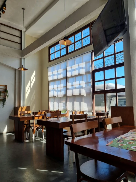 large windows in a dining room next to wooden tables and chairs