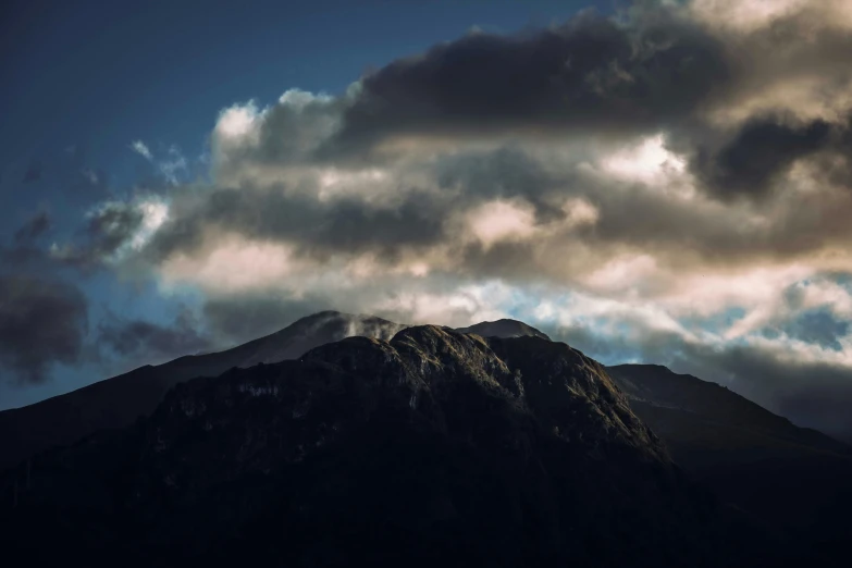 a mountain peak with lots of clouds over it