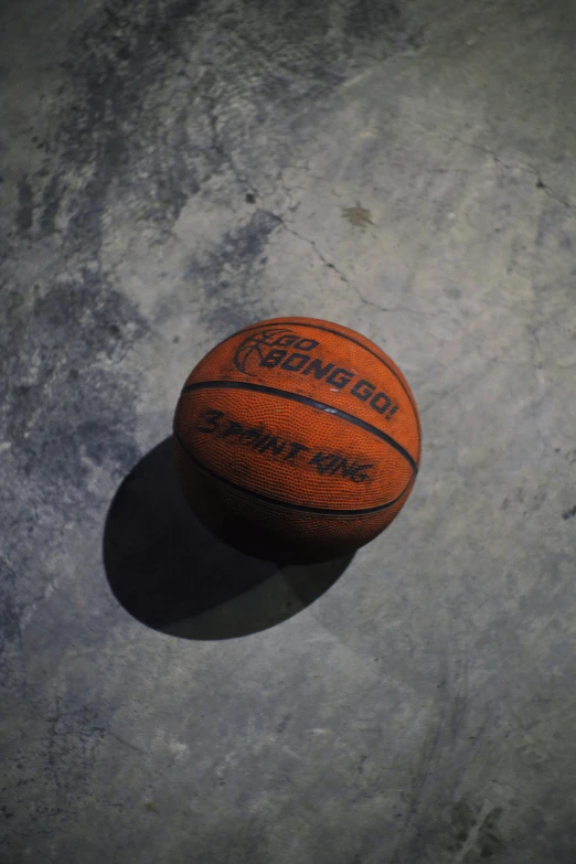 a basketball sitting on top of a cement floor, during the night