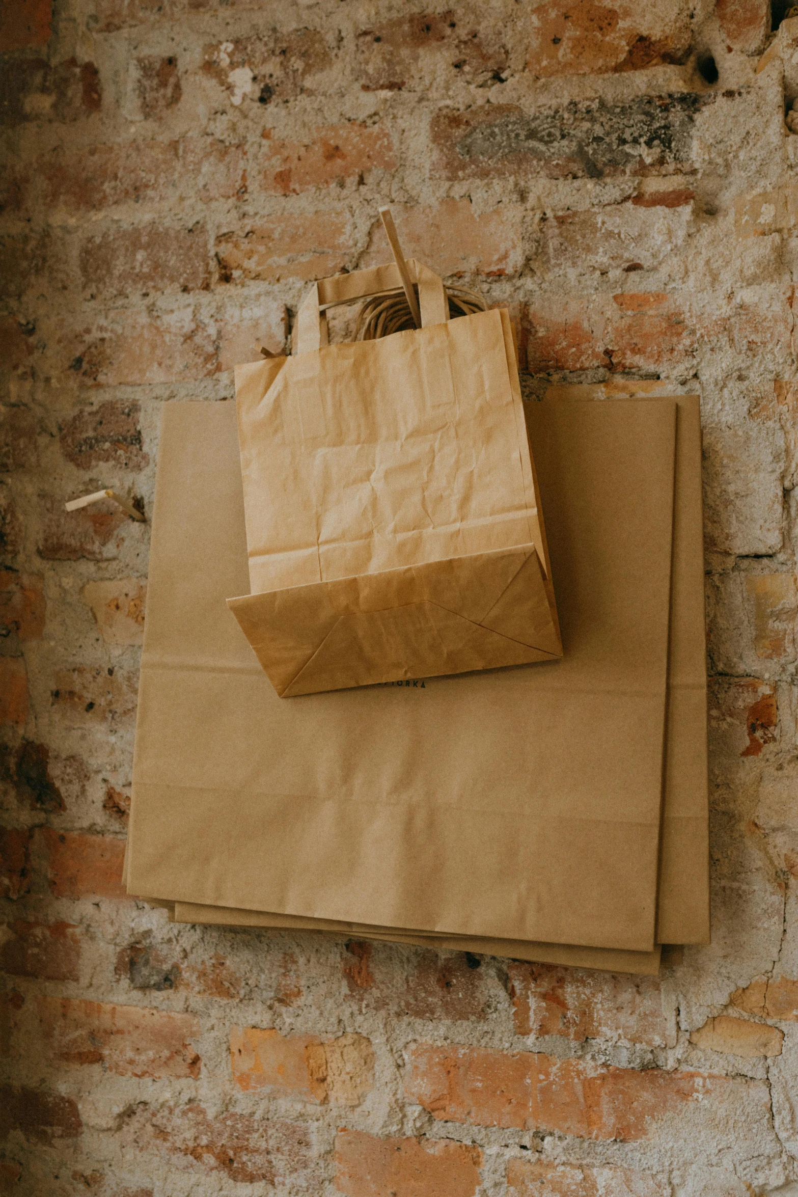 a brown paper bag hanging on a brick wall, pexels contest winner, renaissance, sustainable materials, different sizes, stores, ready to eat