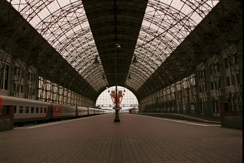 a train sits on tracks in an old metal roof covered station