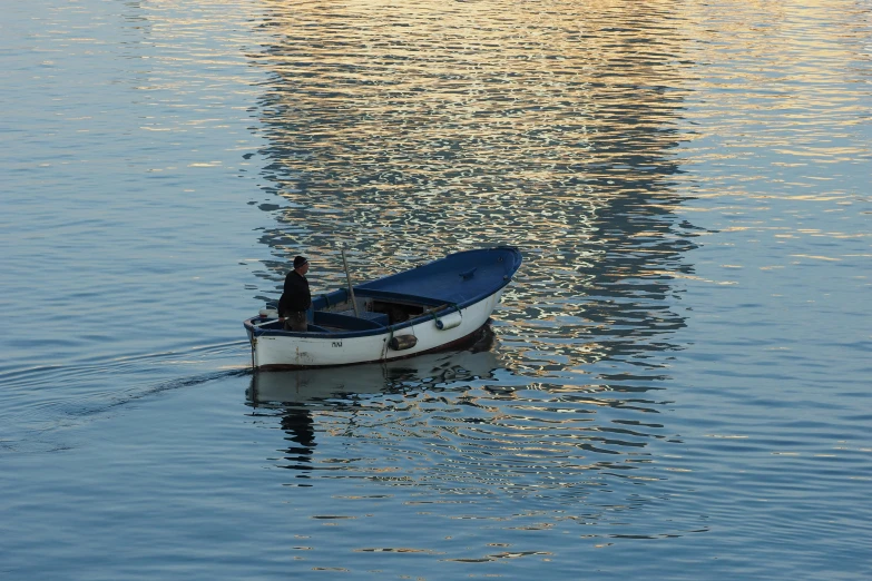 a small boat floating on top of a body of water, pexels contest winner, dappled in evening light, blue reflections, manly, fisherman