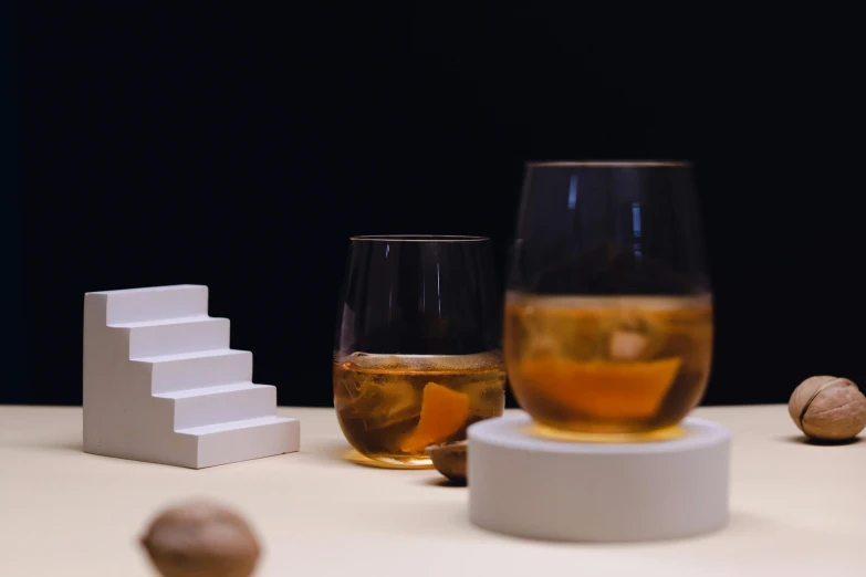 a glass of wine next to a container and a nut on a table