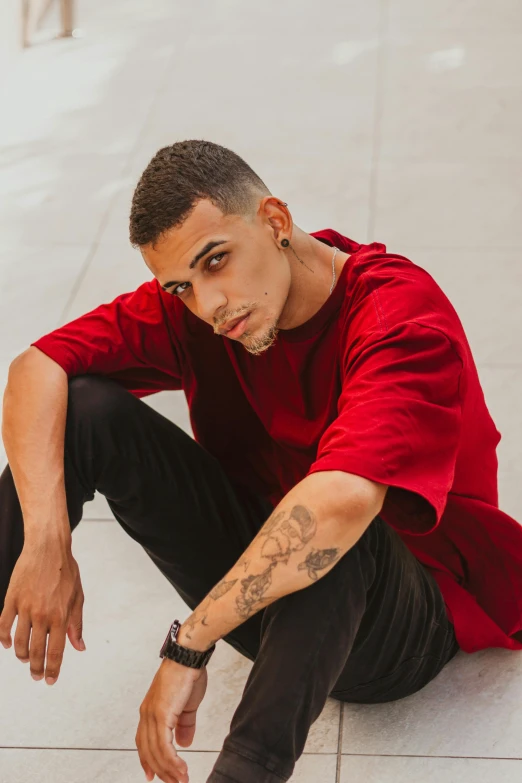 a man in red shirt sitting down on the ground