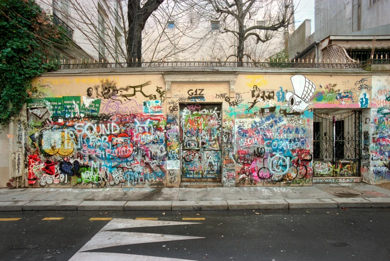 a building covered in lots of graffiti next to a street, conde nast traveler photo, fan favorite, 3 doors, elke