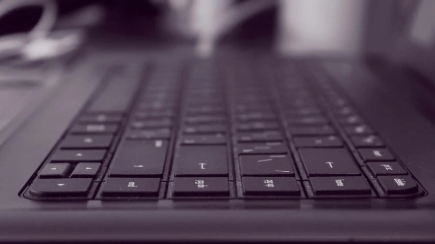 a close up of a keyboard on a laptop, by Carey Morris, pexels, computer art, dark purple tones, desaturated!, it specialist, shot from a low angle