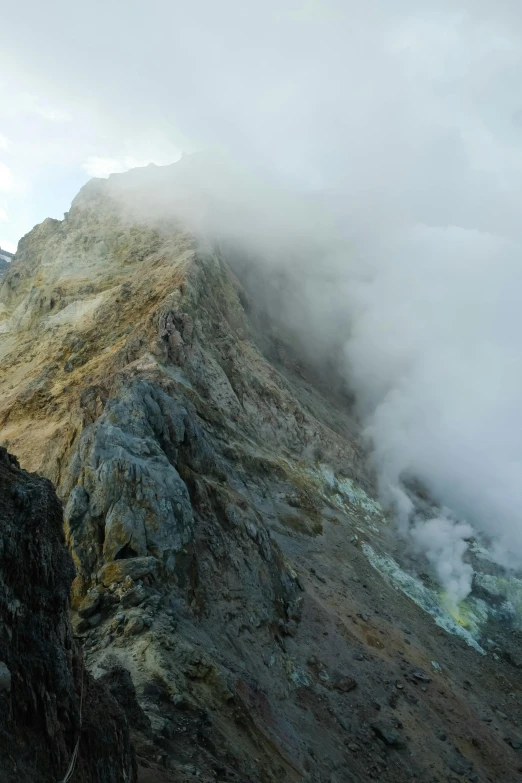 this mountain contains rocky, green plants and low clouds