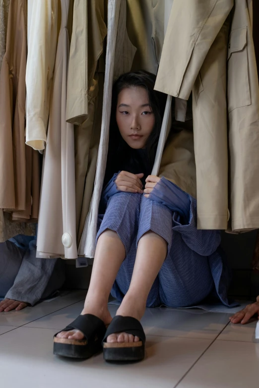 woman sitting on the ground with shoes hanging down and clothes hanging up