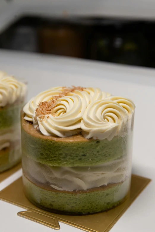 a couple of cakes sitting on top of a table, green and white, upclose, from the side, twirls