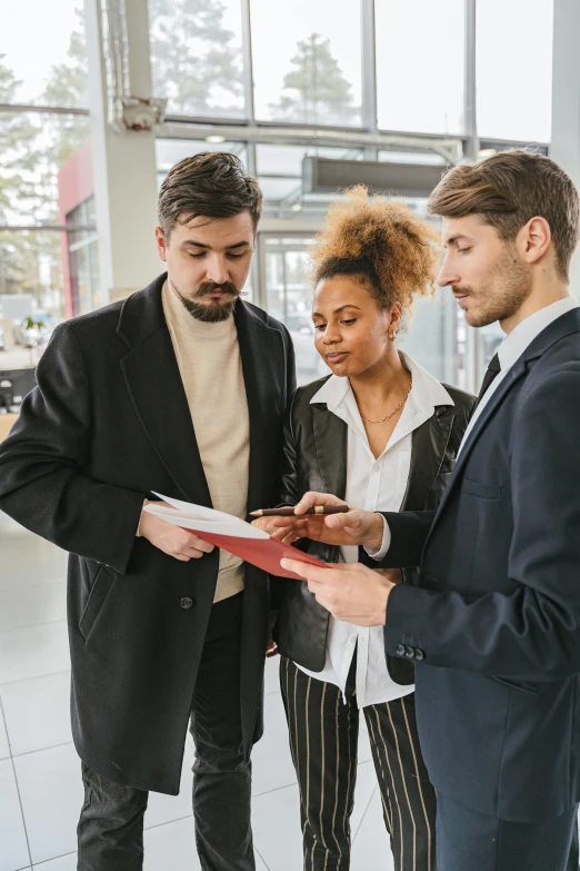 two men and a woman looking at paperwork in a car showroom, pexels contest winner, renaissance, black and red suit, lgbtq, vp of marketing, professional modeling