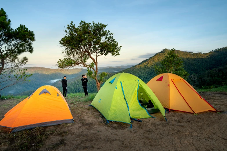 a group of tents sitting on top of a dirt field, pexels contest winner, chartreuse and orange and cyan, avatar image, exterior shot, tawa trees