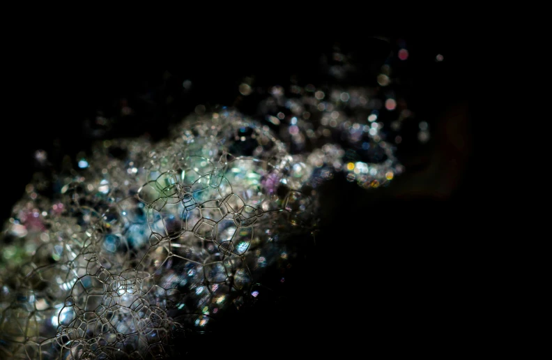 a bunch of bubbles sitting on top of a black surface, a microscopic photo, inspired by Bruce Munro, unsplash, generative art, encrusted with jewels, detailed entangled fibres, hasselblad film bokeh, irridescent ghostly