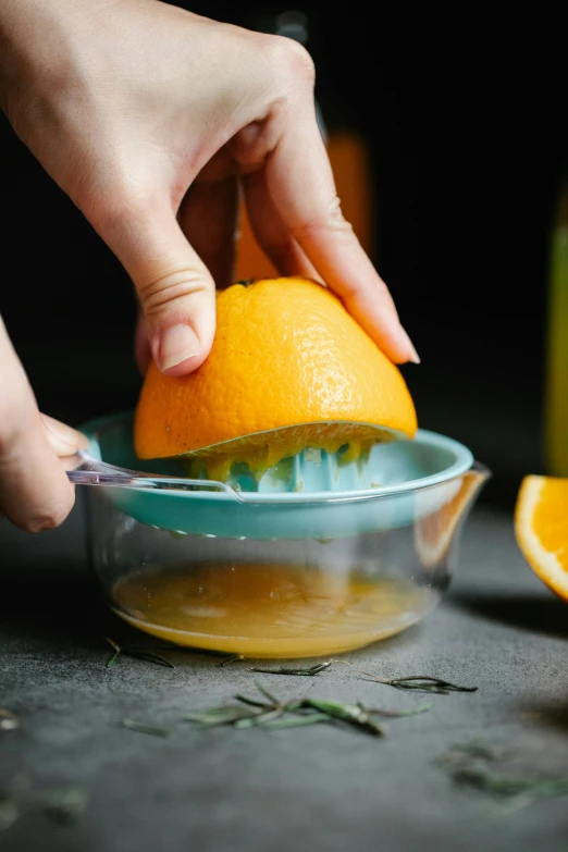 a person squeezing an orange with a juicer, thumbnail, botanicals, bowl, uncropped