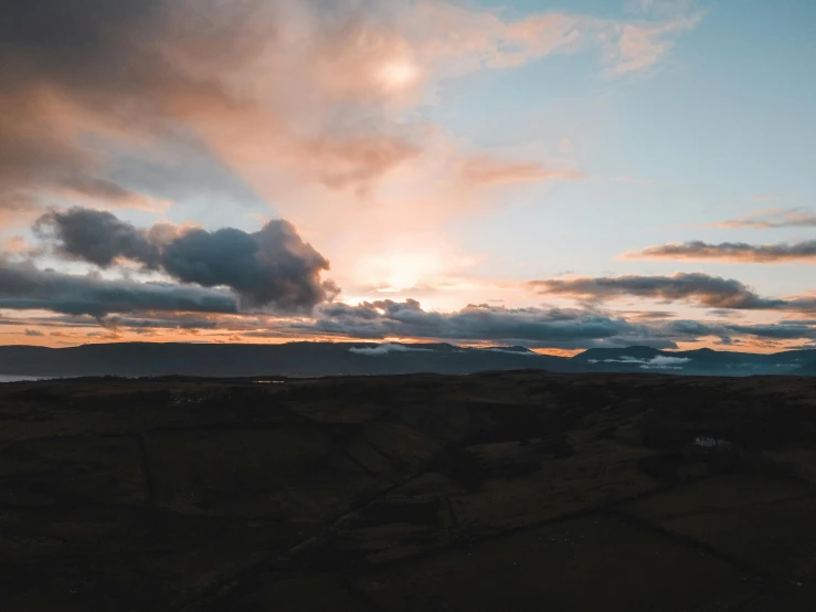 a sky with clouds and the sun in the distance