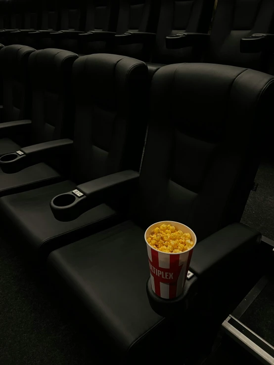 a bucket of popcorn sitting on top of a chair in a movie theater, unsplash contest winner, hyperrealism, in a row, high quality photo, instagram photo, cinematic. by leng jun