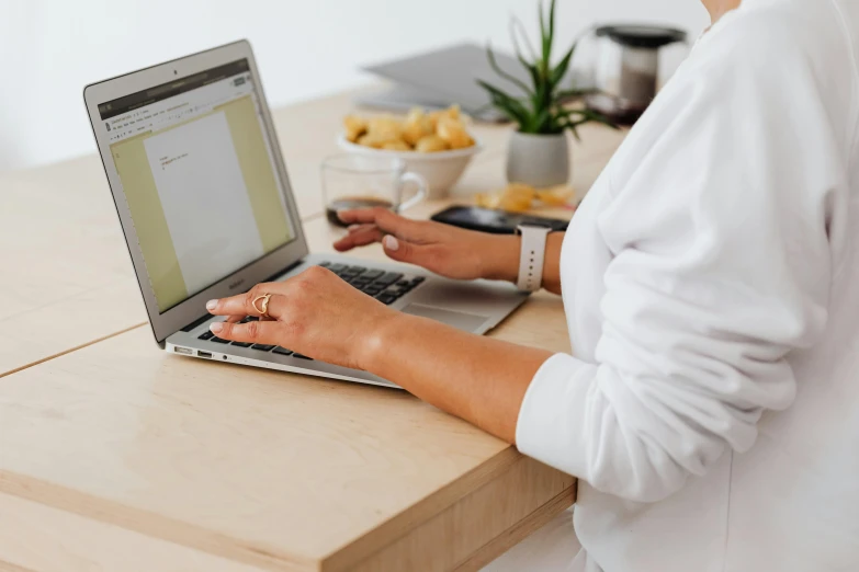 a woman sitting at a table using a laptop computer, trending on pexels, wearing a white button up shirt, nursing, email, background image