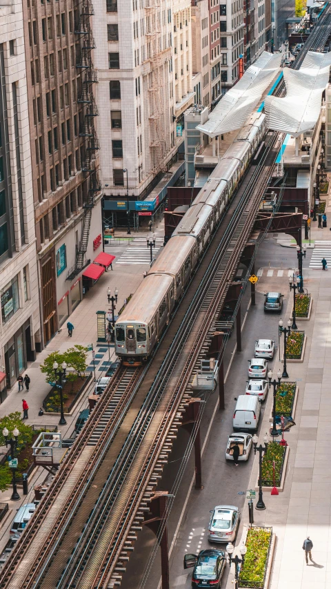 a train traveling through a city next to tall buildings, by Robbie Trevino, pexels contest winner, modern chicago streets, high - angle view, thumbnail, brown