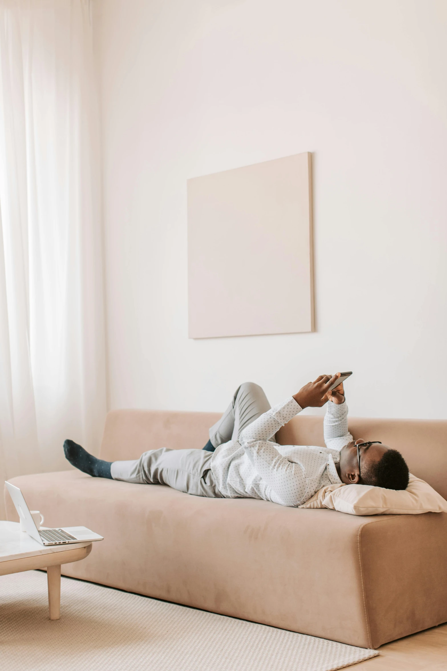 a man laying on a couch in a living room, trending on pexels, cell phone, minimalistic aesthetics, black man, connectivity