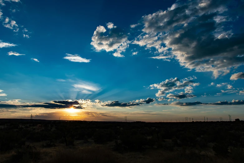 the sun is setting behind the clouds in the sky, by Linda Sutton, unsplash, romanticism, mexican desert, panorama, blue sky, high quality photo