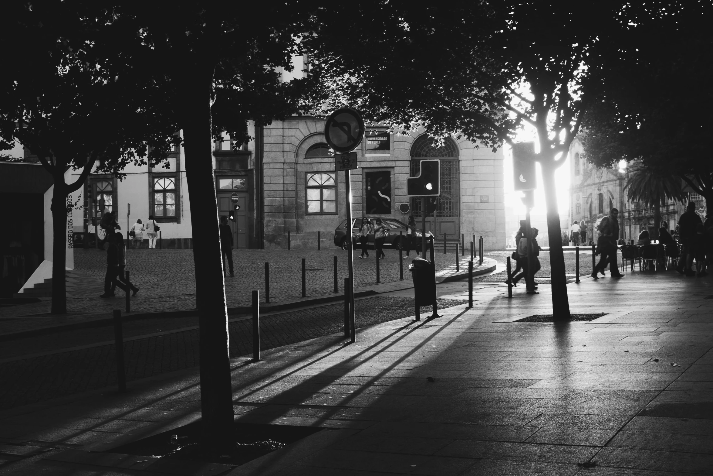 a black and white photo of a city street, a black and white photo, unsplash, evening sun, in a square, paris 2010, summer evening