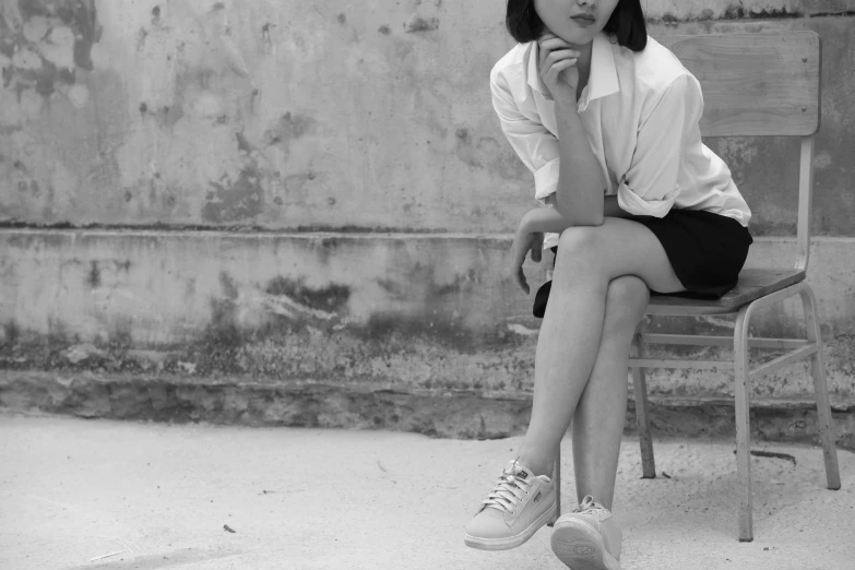 a black and white photo of a woman sitting on a chair, by Wen Zhenheng, minimalism, wearing white sneakers, teenager girl, young cute wan asian face, mixed art