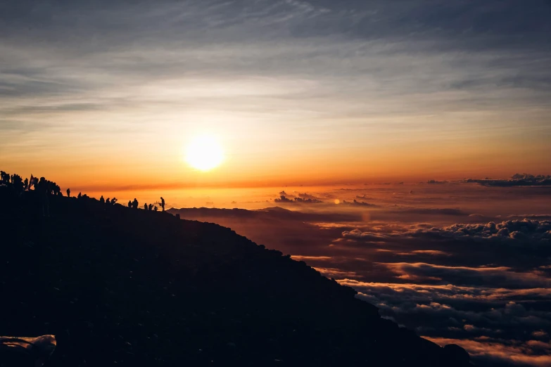 a group of people standing on top of a mountain, pexels contest winner, sumatraism, orange sun set, avatar image, maui, high elevation