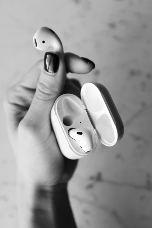 a person holding a pair of airpods in their hand, a black and white photo, trending on pexels, made of glazed, made of plastic, series, anatomical